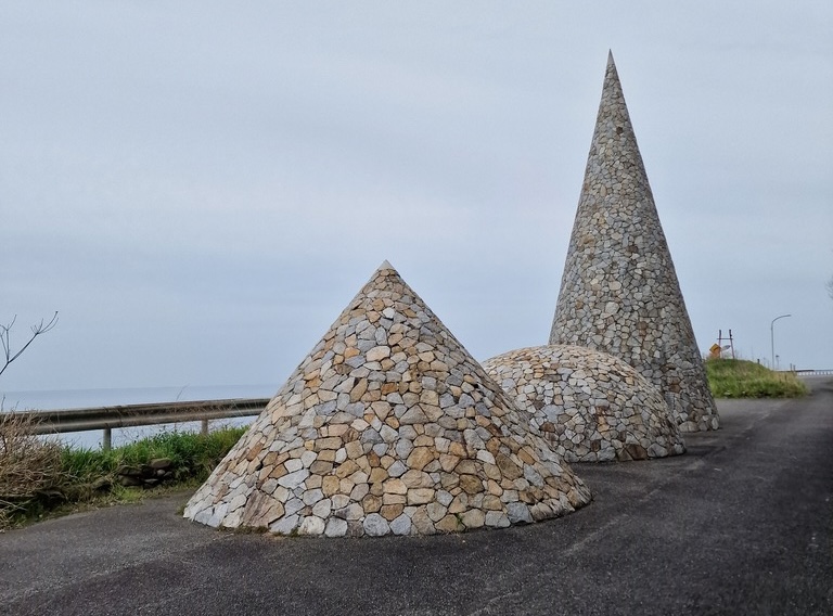 Three big stone figures, two cones, and a dome